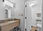 Thumbnail 16 of 23 - A bathroom with a sink, mirror, and toilet.