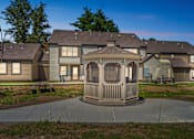 Thumbnail 62 of 66 - A gazebo is in the middle of a concrete patio in front of a house.