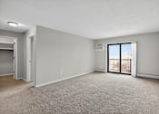 Thumbnail 8 of 32 - A spacious room with a carpeted floor and a sliding glass door leading to a balcony.