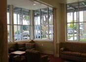 Thumbnail 7 of 23 - A brown couch and chairs are in a room with large windows.
