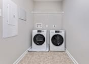 Thumbnail 6 of 7 - Two front loading washing machines in a laundry room.