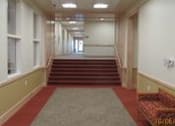 Thumbnail 9 of 23 - A long hallway with a staircase and a bench.
