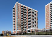 Thumbnail 1 of 28 - A tall red brick building with balconies on the side.