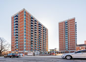 Thumbnail 3 of 28 - Two red brick buildings with balconies in front of a clear sky.