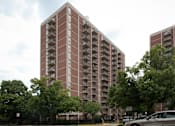 Thumbnail 4 of 28 - A tall red brick apartment building with balconies on the upper floors.