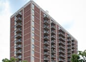 Thumbnail 5 of 28 - A tall red brick apartment building with balconies on each floor.