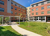 Thumbnail 14 of 23 - A building with a red brick exterior and a white pergola in front.