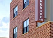 Thumbnail 19 of 23 - A tall brick building with a sign that says "The Cooperage" on it.
