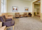 Thumbnail 18 of 23 - A waiting room with striped chairs and a bench.