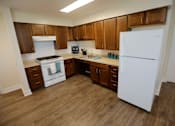 Thumbnail 16 of 28 - A kitchen with a white fridge, brown cabinets and a white stove.