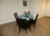 Thumbnail 13 of 28 - A dining table with chairs and a vase of flowers.
