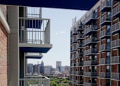 Thumbnail 12 of 28 - A tall building with a balcony overlooking a city skyline.