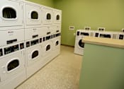 Thumbnail 23 of 28 - A row of white washing machines in a laundromat.