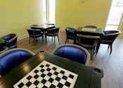 Thumbnail 26 of 28 - A room with a chessboard in the foreground and several chairs and tables.