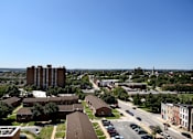 Thumbnail 7 of 28 - A view of a city with a large building in the middle of the frame.