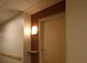 Thumbnail 11 of 23 - A hallway with a brown door and a light on.