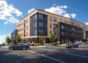 Thumbnail 2 of 10 - A modern building with a parking lot in front.