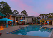 Thumbnail 2 of 23 - A swimming pool is surrounded by a patio with chairs and umbrellas.
