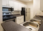 Thumbnail 17 of 23 - A kitchen with a stove, oven, refrigerator, and sink.