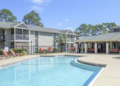 Thumbnail 3 of 23 - A swimming pool in front of a building with a red chair.