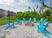 Thumbnail 7 of 23 - A set of blue chairs are arranged around a fire pit.