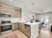Thumbnail 7 of 37 - A modern kitchen with wooden cabinets and stainless steel appliances at The Ashton at East Park Apartments, Georgia, 30144