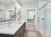 Thumbnail 25 of 37 - A bathroom with a white sink and a glass shower at The Ashton at East Park Apartments, Kennesaw, Georgia