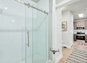 Thumbnail 3 of 37 - A glass shower door in a white bathroom at The Ashton at East Park Apartments, Kennesaw, 30144