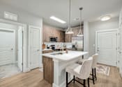 Thumbnail 16 of 37 - A kitchen with a white countertop and a white dining table with two chairs at The Ashton at East Park Apartments, Kennesaw, GA
