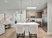Thumbnail 23 of 37 - A modern kitchen with a white island and two chairs at The Ashton at East Park Apartments, Kennesaw, GA