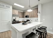 Thumbnail 8 of 37 - A kitchen with a white countertop and black stools at The Ashton at East Park Apartments, Kennesaw, GA, 30144