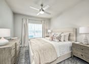 Thumbnail 21 of 37 - A bedroom with a large bed, two nightstands, and a ceiling fan at The Ashton at East Park Apartments, Georgia, 30144
