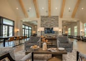 Thumbnail 33 of 37 - A living room with a stone fireplace and wooden beams at The Ashton at East Park Apartments, Kennesaw
