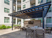 Thumbnail 25 of 47 - Patio with tables and chairs under an awning at The Monroe Apartments, Austin, Texas