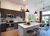 Thumbnail 8 of 47 - a kitchen and living room with a white island and stools at The Monroe Apartments, Austin