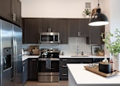 Thumbnail 9 of 47 - a modern kitchen with stainless steel appliances and dark cabinets at The Monroe Apartments, Austin, Texas