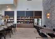 Thumbnail 32 of 47 - a dining room with tables and chairs and a bar with shelves at The Monroe Apartments, Texas, 78741