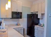 Thumbnail 10 of 14 - Kitchen with black appliances and white cabinets at Emory Woods Apartments, Durham, NC.