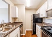 Thumbnail 18 of 23 - A kitchen with black appliances and white cabinets.