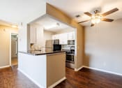 Thumbnail 20 of 23 - A kitchen with a white island and a ceiling fan.