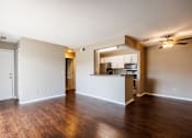 Thumbnail 19 of 23 - A spacious living room with hardwood floors and a kitchen area in the background.