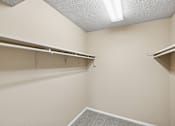 Thumbnail 12 of 17 - Empty walk-in closet with shelves and a carpeted floor.