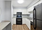 Thumbnail 4 of 15 - White kitchen with black appliances at Governors House, Huntsville, Alabama