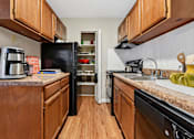 Thumbnail 3 of 51 - Galley kitchen with wood cabinets and granite countertops at The Palms Apartments, Charleston, 29407