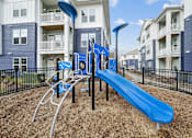 Thumbnail 10 of 28 - A playground with a blue slide and a black fence.at The Parker Leland, Leland  