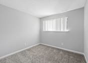 Thumbnail 19 of 24 - A room with a carpeted floor and a window with blinds.