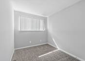 Thumbnail 21 of 24 - A room with a carpeted floor and a window with blinds.