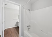 Thumbnail 23 of 24 - A white bathroom with a tub and a doorway.