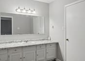 Thumbnail 4 of 24 - A bathroom with a marble countertop and a large mirror above it.