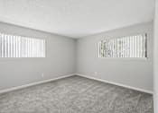 Thumbnail 6 of 24 - A room with two windows and carpeted floor.
